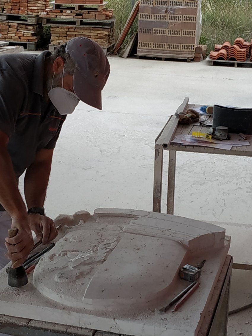 Proceso de talla del escudo en piedra natural en taller. Cincelado detalles