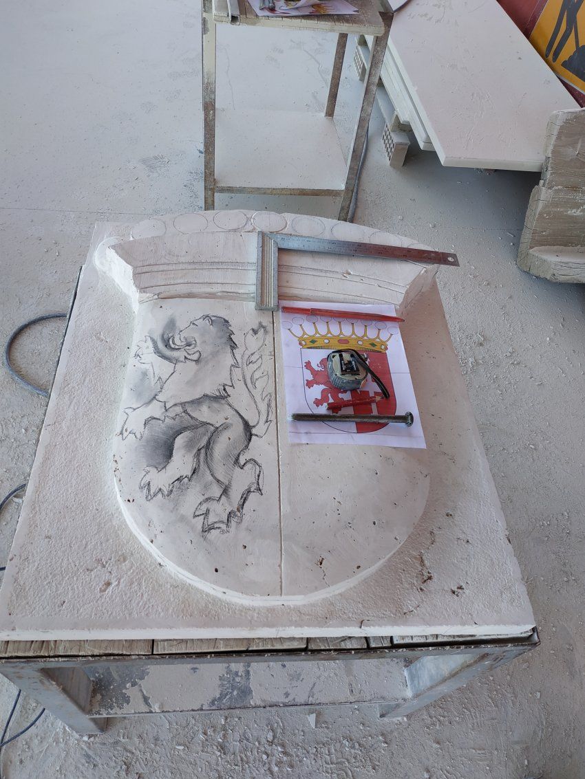 Proceso de talla del escudo en piedra natural en taller. Dibujo detalles